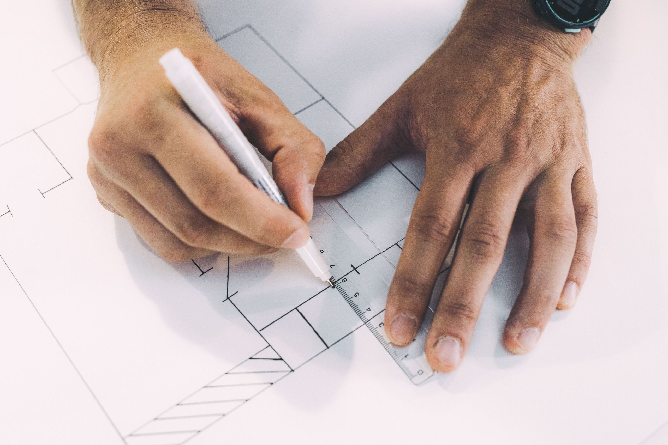 Notice de sécurité pour ERP illustrée par un architecte traçant un plan de bâtiment à la règle