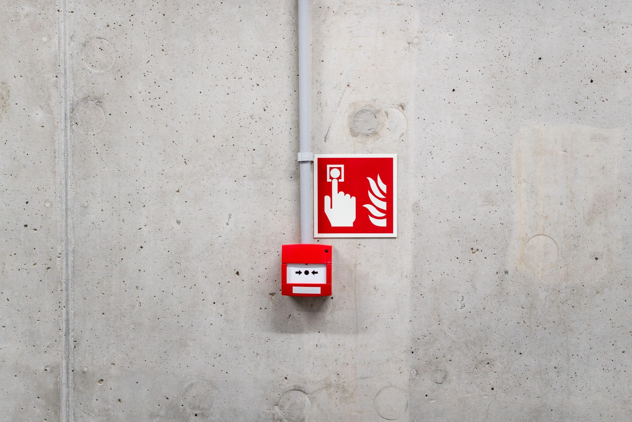 Système d'alarme incendie accroché à un mur en béton gris.